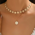 Detail of layered gold daisy necklace featuring white petal pendants on a female model - Daisy Necklace