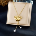 Collana di perle con ciondolo a fiocco dorato e catena a serpente su sfondo di seta blu - Stile Fiocco e Perla Dorata (N3978)