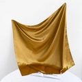 Elegant gold satin square scarf hanging gracefully over a white book and table - 90*90cm / Khaki/Earth Yellow