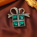 Gros plan détaillé d'une broche en forme de boîte cadeau avec des cristaux vert émeraude - Broche Boîte Cadeau Cristal Carré / Vert