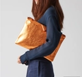Macro shot of metallic orange glitter envelope clutch with secure top metal zipper closure - Orange