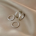Detailed close-up of four silver stacking rings with varied textures on silk fabric - Silver - 4pcs Set Textured Stacking