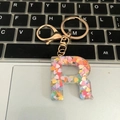Letter R keychain with colorful heart sequins and gold clasp on a laptop keyboard - Letter R