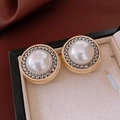 Close-up of vintage button style earrings with large white pearl and gold gear frame - Gold