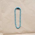 Detailed view of a 2.4mm blue metal beaded chain with secure connector on paper background - Sky Blue