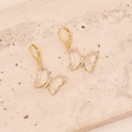 Detail von goldenen Schmetterlingsohrringen mit transparenten Flügeln und Kristallen - Weiß
