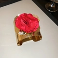 Detail of a wide gold metal cuff bracelet with a large red fabric rose and iridescent leaves - Gold Armband With Red Flower