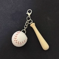 Miniature baseball keychain with white leather ball and wooden bat on black background - White