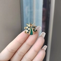 Golden beetle brooch with green crystal inlay held by hand to show compact size - Blue