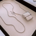 Detail view of silver square woven pendant with sleek snake chain on beige velvet tray - Silver