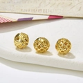 Detailed macro view of three golden hollow filigree beads on a marble stone base - Style 21