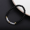 Detail of beaded bracelet featuring matte black stones, pearls, and a gold cross charm - Matte Cross