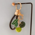 Detail of cherry keychain with sparkling green rhinestones and brown braided leather strap - Green + Heart Lanyard
