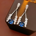 Vue macro de boucles d'oreilles vintage avec zircon bleu foncé et gouttes de cristal blanc - Tige d'oreille en argent - Argent - Bleu