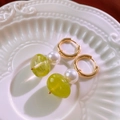 Detailed close-up of vintage resin hoop earring with pearl on white ceramic tray - Gold Green Pearl Huggie