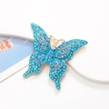 Détail macro d'une broche papillon en alliage ornée de strass bleus et violets brillants - Bleu