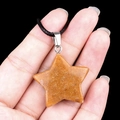 Star-shaped natural carnelian stone pendant on black cord necklace shown in hand - 30mm Yellow Topaz