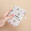 Short white faux leather wallet featuring floral prints and a secure snap closure - White