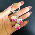 Dettaglio di graziosi ciondoli a zampa di gatto in resina rosa viola e verde su portachiavi - Rosa Rosso