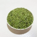 Small polished green peridot crystal chips for decoration in a white ceramic bowl - Peridot