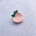 Close-up of a glossy pink peach-shaped acetate hair claw clip with green leaf detail - Peach (2cm)