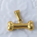 Macro shot of 24k gold plated bone-shaped pendant with polished metallic texture - Bone / Gold