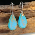 Detailed close-up of Bohemian turquoise teardrop earrings hanging on weathered wood - Turquoise