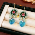 Makroaufnahme handgefertigter Perlenohrringe mit rotem Edelstein und blauem Herzkristall - Blaue Ohrringe