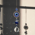 Silver Evil Eye suncatcher with blue crystals casting rainbow reflections on a wall - Round Evil Eye