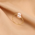 Elegant gold twisted ring featuring two round pink freshwater pearls on silk background - Natural Pink Orange