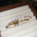 Primer plano detallado de una pulsera de mariposa de circonita dorada en soporte de terciopelo - Bangle / Oro-Blanco