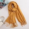 Soft yellow cashmere-feel scarf with fringes and fashion magazine on white background - Turmeric
