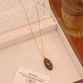 Gros plan d'un collier avec pendentif ovale en œil de tigre sur plateau en velours - Pierre d'Oeil de Tigre