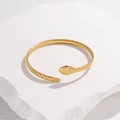 Detail shot of golden snake-shaped bracelet with diamond-patterned scales on white stone - Gold