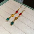 Vintage style gold drop earrings with red, amber, and green oval gems on a display pad - 67# Ear Hook Resin Oval Tassel