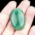 Oval green agate stone held between fingers to show the natural texture and size - Green Aventurine