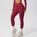 Detail view of high-waist seamless yoga leggings and long sleeve crop top in dark red color - 7100 Trousers - Rouge Red / S