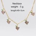 Golden necklace with five purple and green grape zircon pendants on white background - Gold Grape Necklace