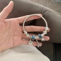 Silver beaded bracelet with Eiffel Tower, rose and blue floral charms held in hand - Tower Bangle