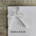 Detailed view of a white pearl bow charm with silver lobster clasp, sized 4.5cm x 4.5cm - No.12 Lobster Clasp 48 Pearl Bow