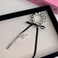 Detalle de pulsera coletero de cuentas plateadas con cinta de seda negra en una bandeja - Coletero De Perlas Plateadas
