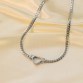 Gros plan détaillé d'une chaîne cubaine argentée avec pendentif cœur sur de la soie - Collier / Acier