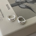 Close-up van kleine S925 sterling zilveren oorringen op een vintage boek kaft - 925 zilver / Zilver