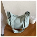 Detail of light green crescent nylon bag with small round coin purse charm on a wood table - Green