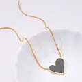 Detailed close-up of a heart pendant on a gold snake chain in a white ceramic dish - Black Heart