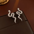 Macro detail of silver snake earrings with zircon pavé on brown leather jewelry box - Silver Plated (Silver Pin)
