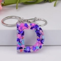Detail of letter D resin keychain with colorful purple pink and blue stone chips - Letter D