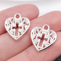Pair of silver heart-shaped pendants with hollow cross patterns held on fingers for size - Heart Pattern 16x14mm (1.2g)
