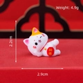 Cute white resin fortune cat figurine holding lucky gold coin on festive red background - Lying Lucky Cat