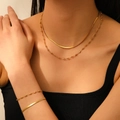 Détail du collier et bracelet double couche en acier inoxydable doré porté par un mannequin - Parure de Bijoux Double Couche Lame Perle d'Acier Coeur Doré (T306-T207)